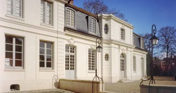 Façade de la Maison des Musiciens Italiens à Versailles, bâtiment classique clair à toiture d'ardoise, avec ses lanternes en fer forgé.